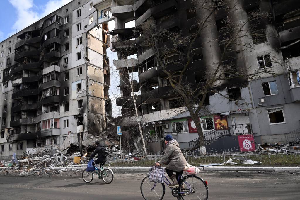 Pessoas andam de bicicleta passando por pr&eacute;dios destru&iacute;dos na cidade de Borodianka, a noroeste de Kiev -