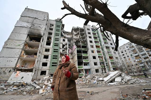 Uma mulher em frente a um prédio de apartamentos destruídos em Chernigiv - Uma mulher em frente a um prédio de apartamentos destruídos em Chernigiv -