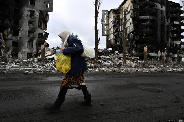 Uma mulher caminha em frente a prédios destruídos na cidade de Borodianka - Uma mulher caminha em frente a prédios destruídos na cidade de Borodianka -
