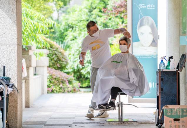 Um voluntário da comunidade, corta o cabelo de um residente em um complexo residencial, durante o bloqueio de Covid-19 no distrito de Pudong, em Xangai, em 1º de maio de 2022. Um voluntário da comunidade, corta o cabelo de um residente em um complexo residencial, durante o bloqueio de Covid-19 no distrito de Pudong, em Xangai, em 1º de maio de 2022.
