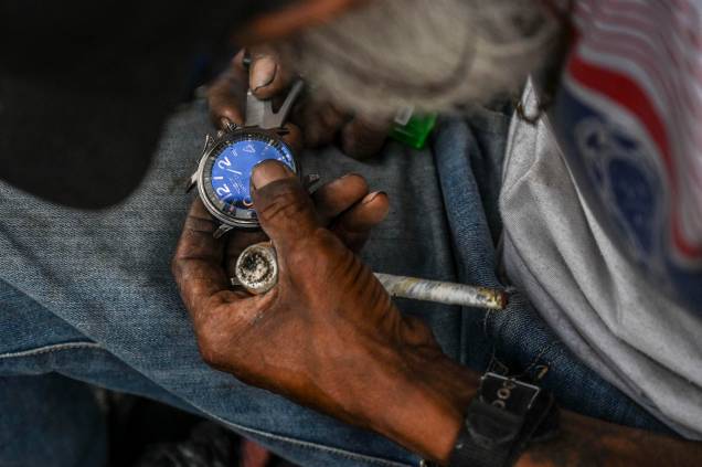 Um homem conserta um relógio enquanto segura um cachimbo de crack, cocaína misturada com pasta de coca e outras substâncias, no centro de Medellín, Colômbia, em 25 de fevereiro de 2022. Um homem conserta um relógio enquanto segura um cachimbo de crack, cocaína misturada com pasta de coca e outras substâncias, no centro de Medellín, Colômbia, em 25 de fevereiro de 2022.