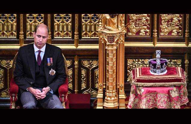 O príncipe britânico William, Duque de Cambridge, sentado ao lado da Coroa do Estado Imperial, na Câmara dos Lordes, durante a Abertura do Parlamento, em Londres, em 10 de maio de 2022. O príncipe britânico William, Duque de Cambridge, sentado ao lado da Coroa do Estado Imperial, na Câmara dos Lordes, durante a Abertura do Parlamento, em Londres, em 10 de maio de 2022.