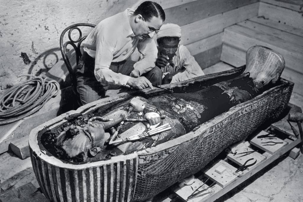 Howard Carter (1873-1939) english egyptologist near golden sarcophagus of Tutankhamon (mummy) in Egypt in 1922 (photo Harry Burton) EM EQUIPE - Luxor, 1922: Carter, a tumba e um de seus anônimos assistentes -