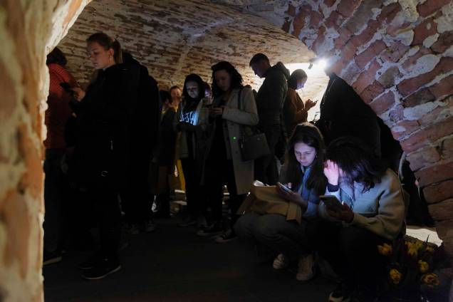 Pessoas compartilham espaços em um porão de um edifício histórico que está sendo usado como abrigo antiaéreo durante um alerta de ataque aéreo na cidade de Lviv, no oeste da Ucrânia. Pessoas compartilham espaços em um porão de um edifício histórico que está sendo usado como abrigo antiaéreo durante um alerta de ataque aéreo na cidade de Lviv, no oeste da Ucrânia.