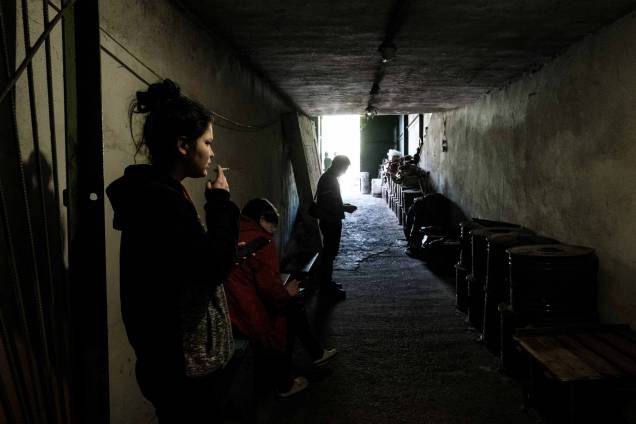 Uma mulher fumando um cigarro na entrada do bunker da fábrica Ostchem em Severodonetsk, leste da Ucrânia, em 27 de abril de 2022, em meio à invasão russa da Ucrânia. Uma mulher fumando um cigarro na entrada do bunker da fábrica Ostchem em Severodonetsk, leste da Ucrânia, em 27 de abril de 2022, em meio à invasão russa da Ucrânia.