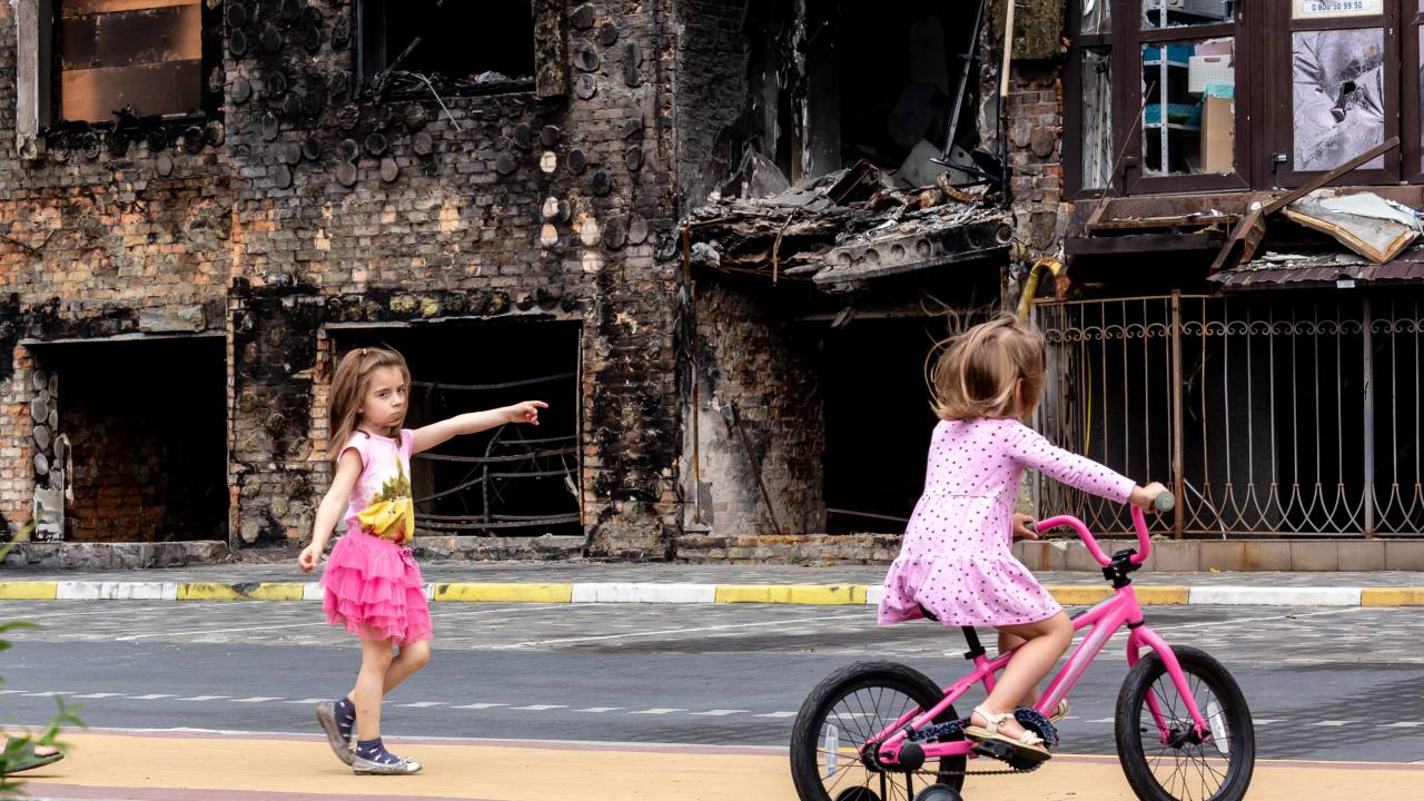 Two girls are seen in front a residential area affected by bombardment - June 14, 2022 in Bucha, Ukraine. As the Russian Federation invaded Ukraine more than 3 and a half months ago, fierce fighting continues in the East of the country. Some of the most devastated towns since the beginning of the conflict - Irpin and Bucha - build their way to normality. More and more civilians get back to their homes and reestablish their lives. (Photo by Dominika Zarzycka/NurPhoto via Getty Images)