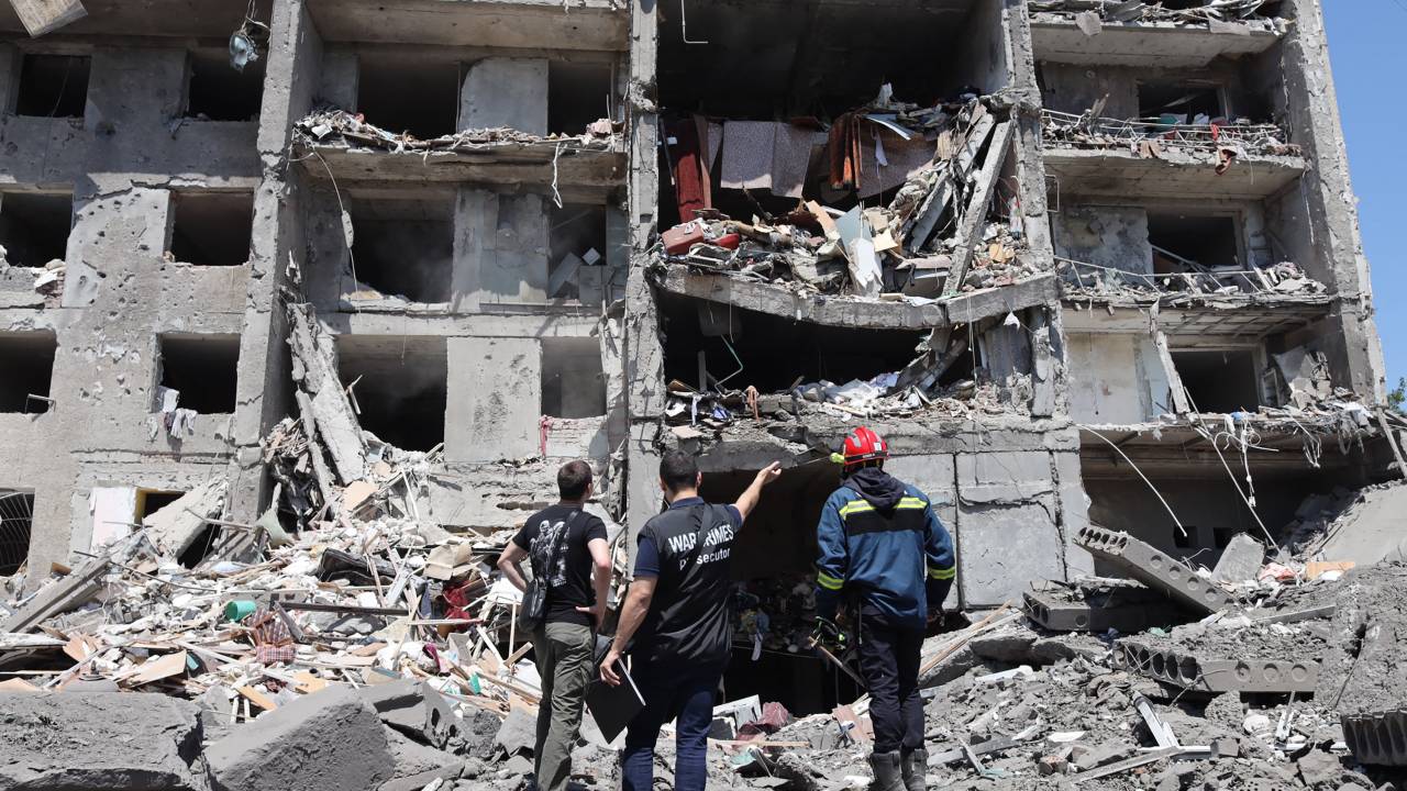 A war crimes prosecutor (C) and a rescuer (R) and a civil, look at a destroyed building after being hit by a missile strike in the Ukrainian town of Serhiivka, near Odessa, killing at least 18 people and injuring 30, on July 1, 2022. - During the night from June 30 to July 1, 2022, two missiles were fired by a "strategic aircraft" from the Black Sea, hitting buildings, according to the Ukrainian emergency services. (Photo by Oleksandr GIMANOV / AFP)