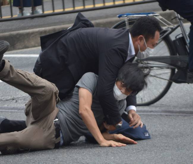 JAPAN-POLITICS-ATTACK-ABE A man (bottom) suspected of shooting former Japanese prime minister Shinzo Abe is tackled to the ground by police at Yamato Saidaiji Station in the city of Nara on July 8, 2022. - Shinzo Abe was shot at a campaign event on July 8, a government spokesman said, as local media reported the nation's longest-serving premier was showing no vital signs. (Photo by Yomiuri Shimbun / AFP) / Japan OUT / NO ARCHIVES