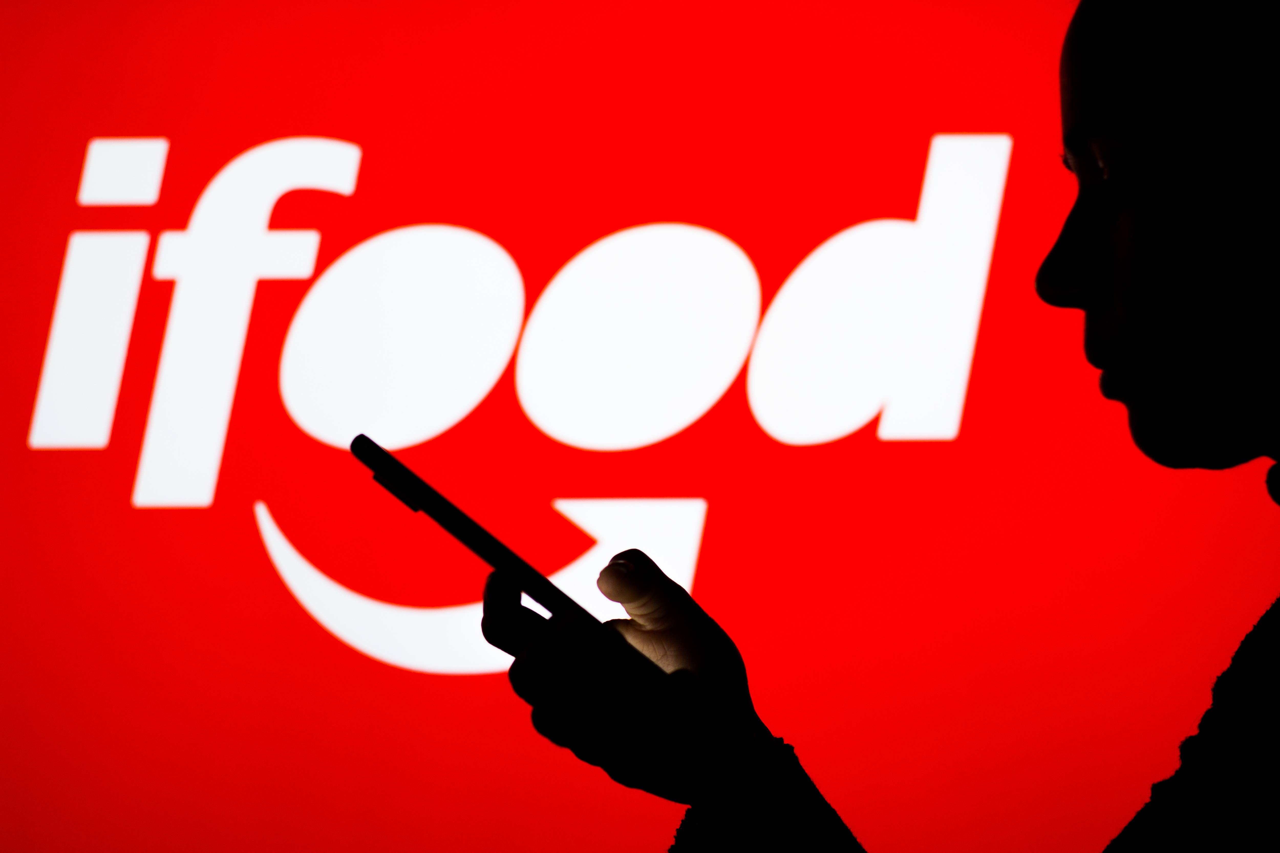 BRAZIL - 2022/04/18: In this photo illustration the iFood logo seen in the background of a silhouette woman holding a mobile phone. (Photo Illustration by Rafael Henrique/SOPA Images/LightRocket via Getty Images)
