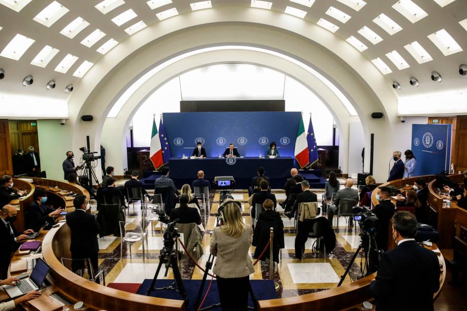 O primeiro-ministro italiano Mario Draghi (C), o ministro da Saúde italiano Roberto Speranza (E) e a ministra italiana de Assuntos Regionais Maria Stella Gelmini, durante a coletiva de imprensa para ilustrar as novas medidas adotadas pelo Governo italiano para conter a propagação do Covid-19 em Roma, Itália, 24/11/2021.