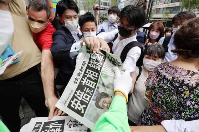 As pessoas se aglomeram para pegar um jornal extra sobre o assassinato do ex-primeiro-ministro japonês Shinzo Abe, em Tóquio /08/07/2022. As pessoas se aglomeram para pegar um jornal extra sobre o assassinato do ex-primeiro-ministro japonês Shinzo Abe, em Tóquio /08/07/2022.