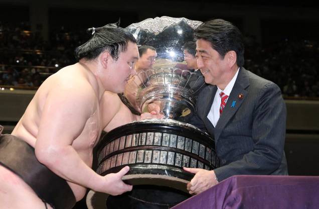 O grande campeão se Sumô "yokozuna", Hakuho, recebe a taça do ex primeiro-ministro Shinzo Abe após vencer o torneio nacional de Sumô em Tóquio. 22/05/2016. O grande campeão se Sumô "yokozuna", Hakuho, recebe a taça do ex primeiro-ministro Shinzo Abe após vencer o torneio nacional de Sumô em Tóquio. 22/05/2016.