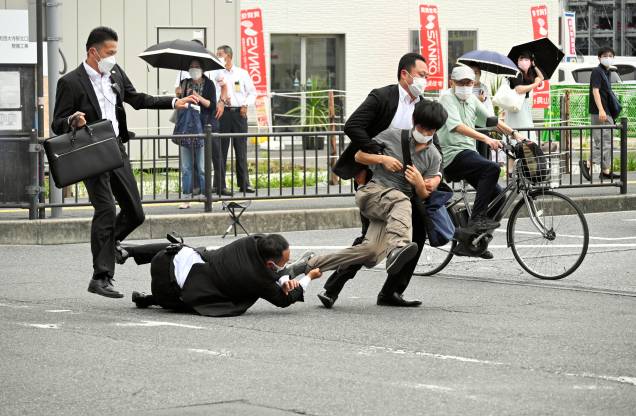 A polícia de segurança aborda um suspeito de ter atirado no ex-primeiro-ministro Shinzo Abe do lado de fora da estação Yamato-Saidaiji em Nara, Japão, 08/07/2022. O suspeito identificado como Tetsuya Yamagami foi preso e levado sob custódia. A polícia de segurança aborda um suspeito de ter atirado no ex-primeiro-ministro Shinzo Abe do lado de fora da estação Yamato-Saidaiji em Nara, Japão, 08/07/2022. O suspeito identificado como Tetsuya Yamagami foi preso e levado sob custódia.