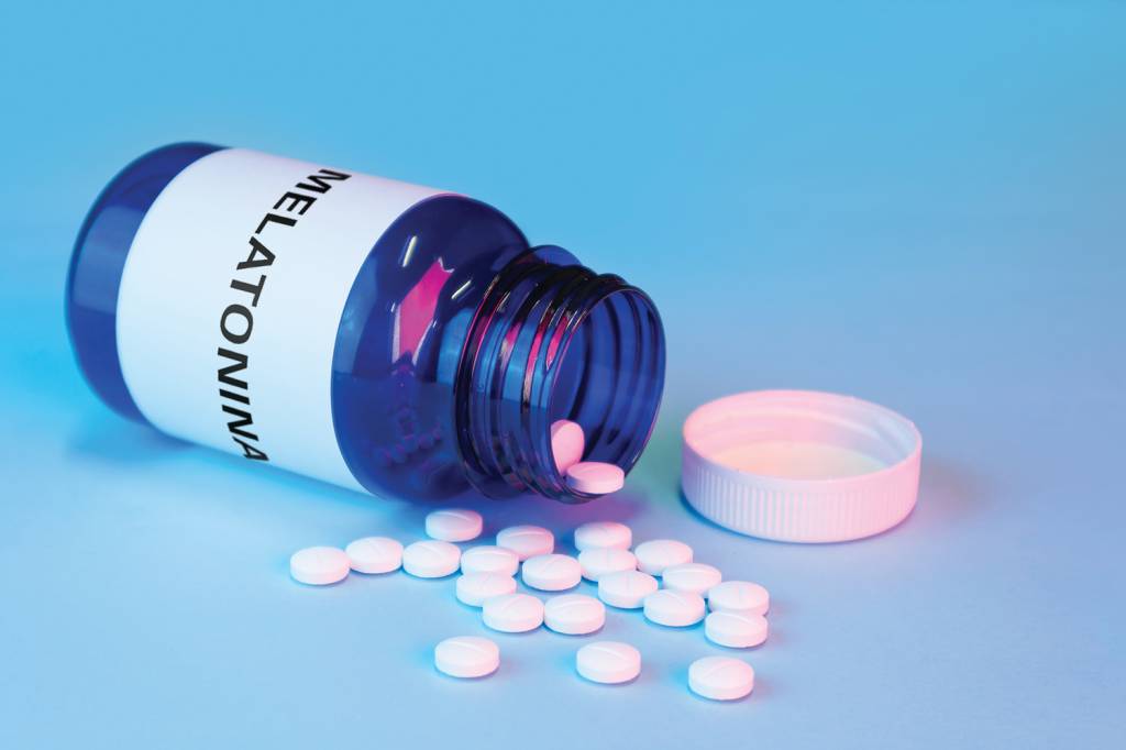 blue white label medication bottle with loose pills, mockup ALERTA - Melatonina: liberada no Brasil, em alta nos Estados Unidos -