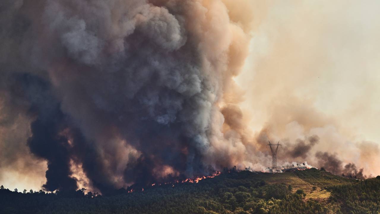 MAFRA, PORTUGAL - JULY 31: A large plume of smoke and flames are seen at a forest fire being fought by 321 firefighters, 84 vehicles and 9 specialized aircraft on July 31, 2022 in Mafra, Portugal. The rise in temperatures this weekend is causing a new wave of forest fires in the country, especially in the central and northern regions. The fires that most concern the authorities this Sunday afternoon are active in the municipalities of Ourém, Mafra and Paços de Ferreira, with some 700 firefighters and 20 aerial means fighting them. (Photo by Horacio Villalobos#Corbis/Corbis via Getty Images)