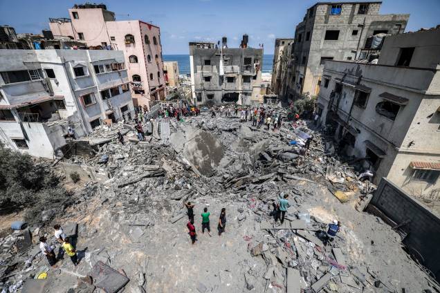 Palestinos inspecionam ruínas de um prédio destruído por um ataque aéreo israelense na Cidade de Gaza, em 06/08/2022. Palestinos inspecionam ruínas de um prédio destruído por um ataque aéreo israelense na Cidade de Gaza, em 06/08/2022.