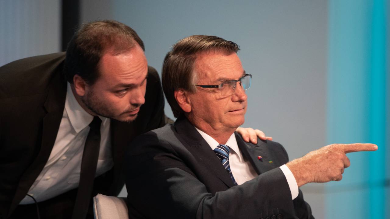 AME1001. RIO DE JANEIRO (BRASIL), 29/09/2022.- El presidente y candidato a reelección, Jair Bolsonaro (d), señala junto a su hijo Carlos durante un debate hoy, con los demás candidatos, en los estudios de TV Globo en Río de Janeiro (Brasil). Las elecciones para presidente en Brasil se llevarán a cabo el próximo domingo 2 de octubre y las encuestas recientes muestran a Lula y a Bolsonaro como los favoritos. EFE/André Coelho