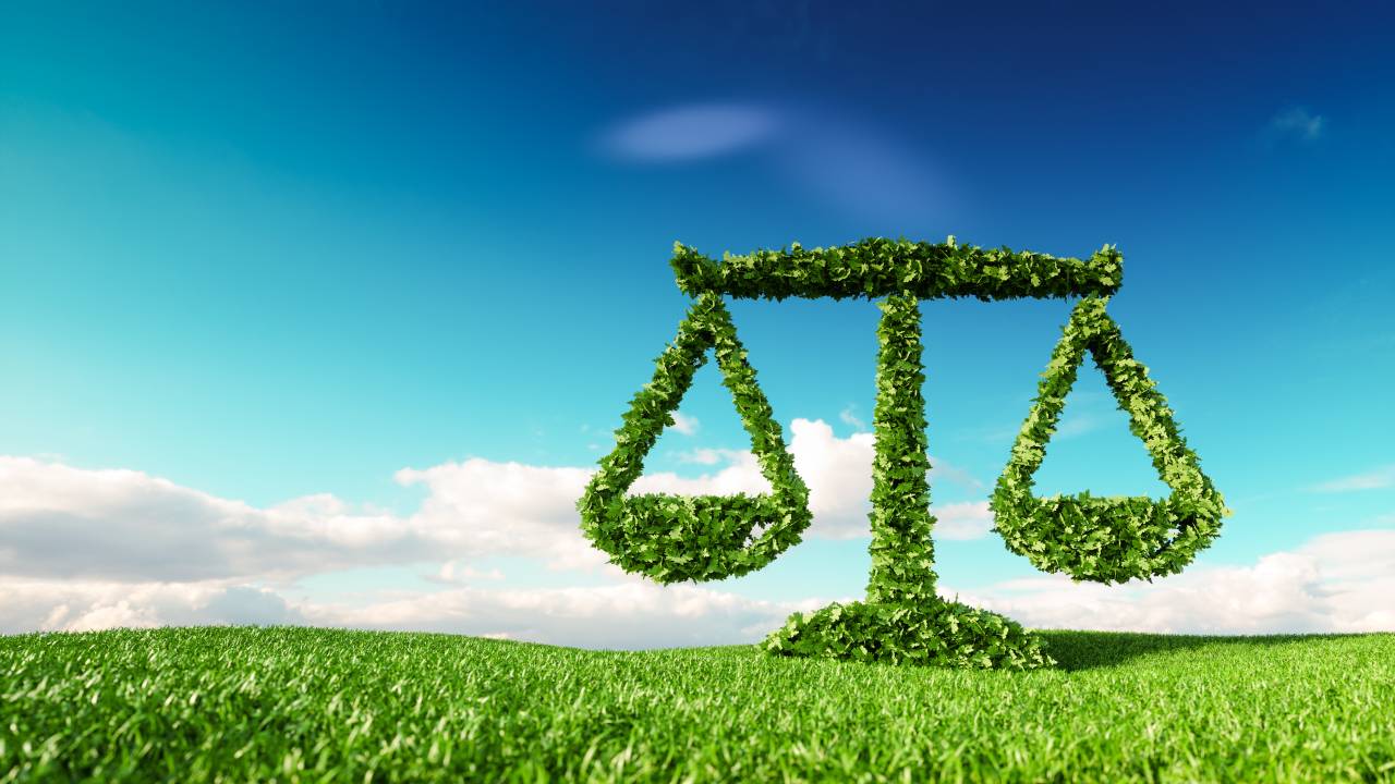 Eco friendly law, politics and eco balance concept. 3d rendering of scale icon on fresh spring meadow with blue sky in background.