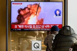 People sit near a television showing a news broadcast with file footage of a North Korean missile test, at a railway station in Seoul on November 18, 2022. - A suspected intercontinental ballistic missile launched by North Korea on Friday is believed to have fallen in Japan's exclusive economic waters, Japanese Prime Minister Fumio Kishida said. (Photo by Anthony WALLACE / AFP)