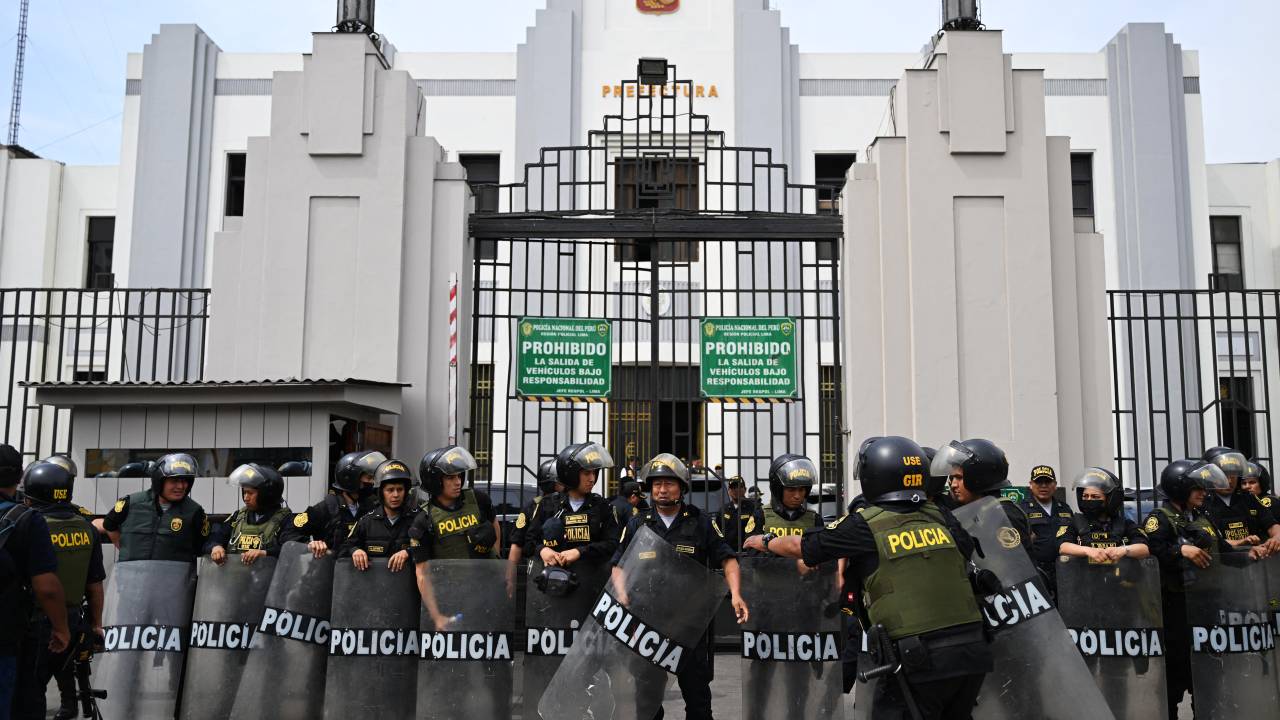 Members of the Peruvian police stand guard outside the Lima Prefecture, where Peru's President Pedro Castillo is alleged to be, in Lima, on December 7, 2022. - Peru's President Pedro Castillo dissolved Congress on December 7, 2022, announced a curfew and said he will form an emergency government that will rule by decree, just hours before the legislature was due to debate a motion of impeachment against him. (Photo by ERNESTO BENAVIDES / AFP)