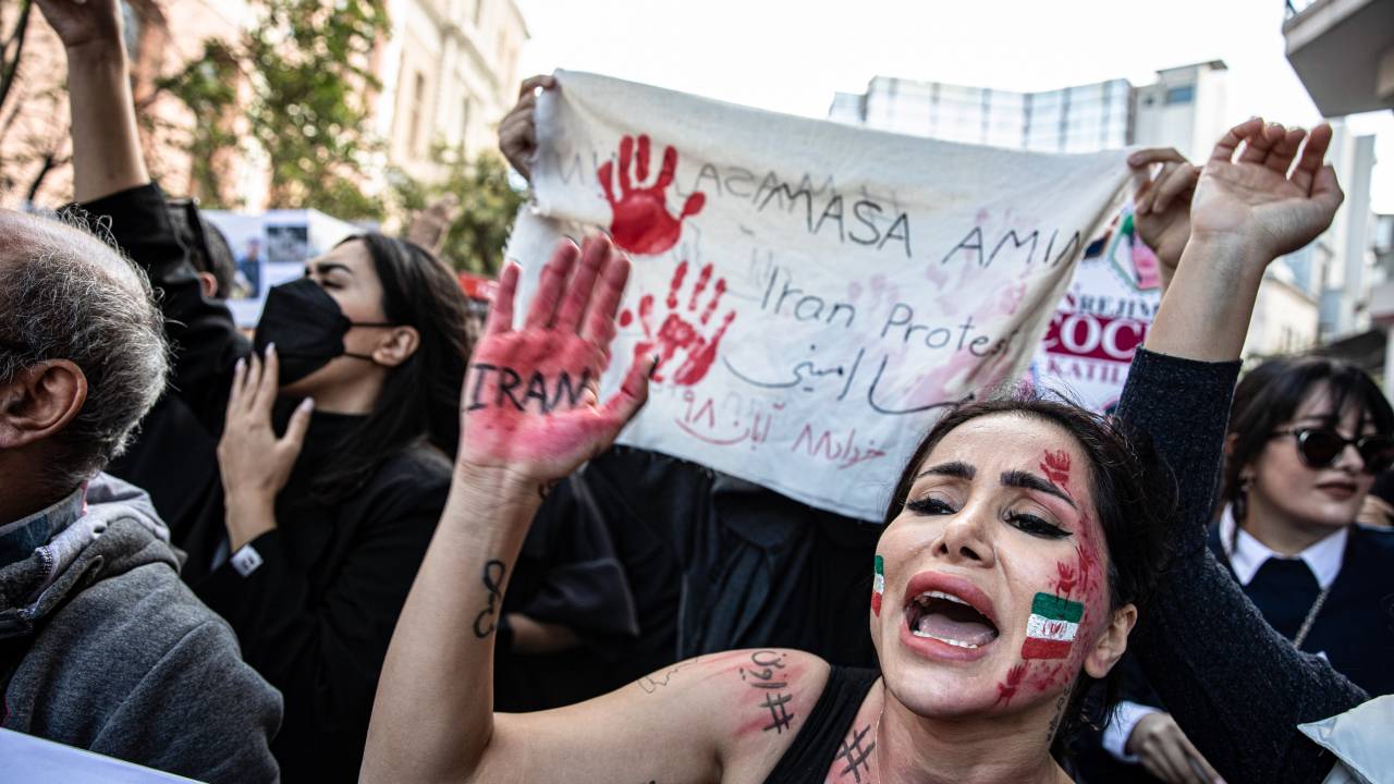 A protester with the Iranian flag painted on her face raises
