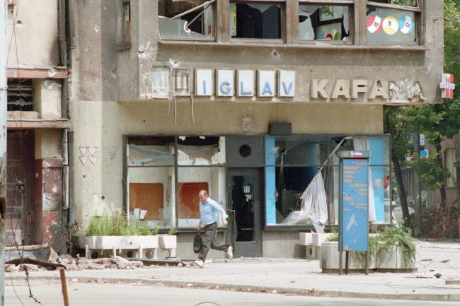 Homem bósnio corre em Sarajevo durante a guerra civil Homem bósnio corre em Sarajevo durante a guerra civil