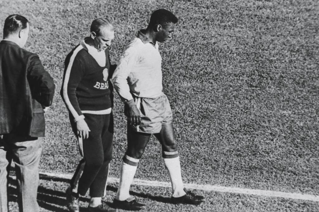 Pelé-ao-lado-de-Aymoré-Moreira,-técnico-da-seleção-brasileira,-saindo-machucado-do-jogo-contra-a-Tchecoslováquia,-no-Estádio-Sausalito..jpg CAÇADO - Em 1962: mancando como um cão atropelado de Nelson Rodrigues -