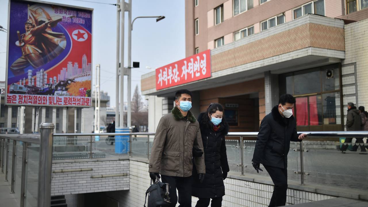 Pessoas de máscara caminham em Pyongyang. 22/01/2023