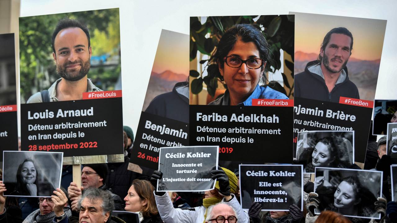 Demonstrators hold portraits of French detainees in Iran during a protest in their support at the "Esplanade du Trocadero" in Paris on January 28, 2023. - Paris said on January 25 that Foreign Minister Catherine Colonna in telephone talks with Iranian counterpart Hossein Amir-Abdollahian demanded the "immediate release of the seven French hostages arbitrarily detained" by Tehran. (Photo by STEPHANE DE SAKUTIN / AFP)