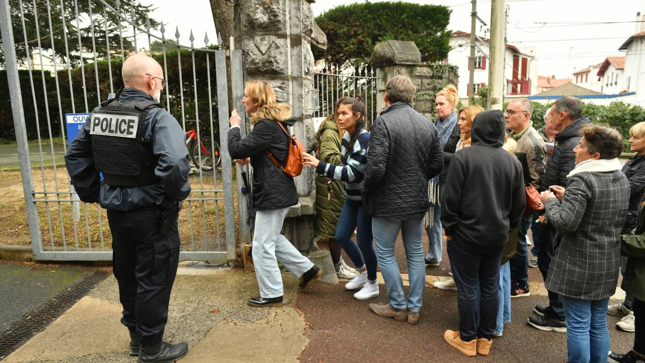 Onlookers gather at the entrance of Saint-Thomas dAquin middle school where a teacher died after being stabbed by a student, in Saint-Jean-de-Luz, southwestern France, on February 22, 2023. - A teacher at a school in southwest France was killed on February 22, in a stabbing attack by a teenage pupil during her class, the regional prosecutor said. The teacher, in her 50s, was teaching a class at the school in the seaside town of Saint-Jean-de-Luz when the pupil attacked her with a knife. (Photo by GAIZKA IROZ / AFP)