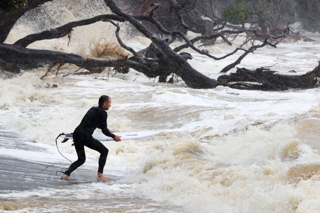 Cyclone Gabrielle Brings Stong Winds And Heavy Rain To New Zealand Um surfista se dirige para ondas grandes e mares agitados do ciclone Gabrielle na Reserva Marinha de Goat Island