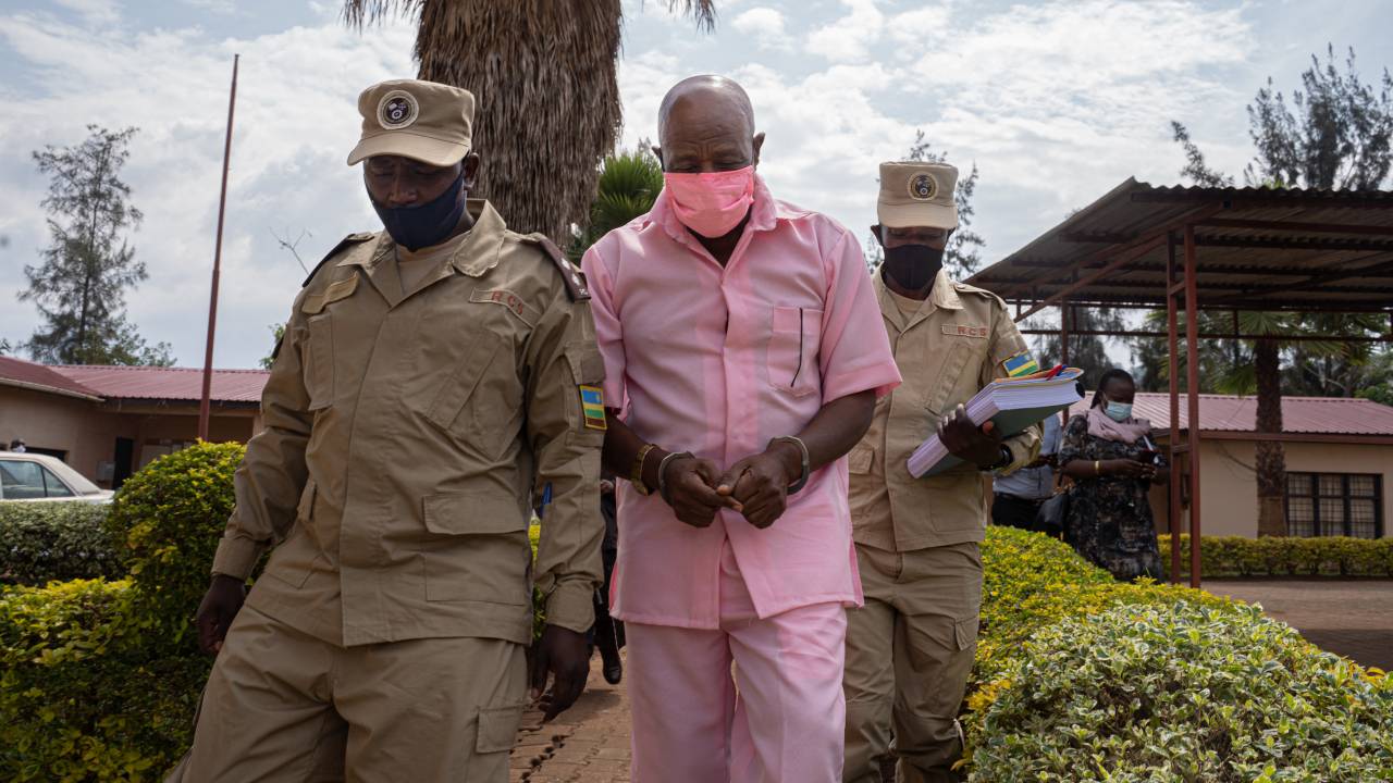 (FILES) In this file photo taken on October 02, 2020 "Hotel Rwanda" hero Paul Rusesabagina (C) in the pink inmate's uniform arriving at Nyarugenge Court of Justice in Kigali, Rwanda, surrounded by guards of Rwanda Correctional Service (RCS). - Rwanda has commuted the 25-year prison sentence of ailing "Hotel Rwanda" hero Paul Rusesabagina, a government spokeswoman told AFP on on March 24, 2023.Rusesabagina's sentence imposed in September 2021 has been "commuted by presidential order," spokeswoman Yolande Makolo said of the case which roused international concern in the West and among rights campaigners. (Photo by Simon Wohlfahrt / AFP)