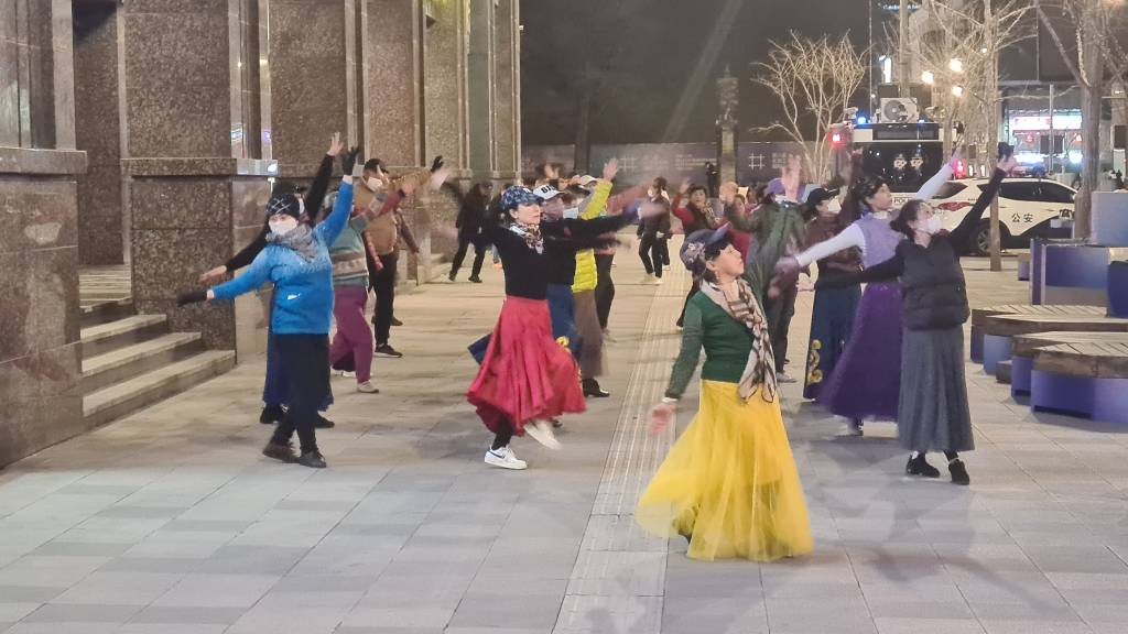 DOIS PARA L&Aacute;, DOIS PARA C&Aacute; - Mulheres dan&ccedil;am na rua Wangfujing , centro de Pequim: a face d&oacute;cil de uma China que range os dentes para o mundo ocidental