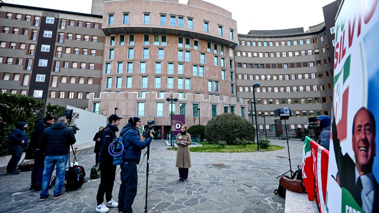 A banner reading "Go Silvio!" is seen as journalists wait outside the San Raffaele hospital where former Italian Prime Minister, Silvio Berlusconi is hospitalised at San Raffaele hospital in Milan on April 8, 2023. - The 86-year-old media mogul and senator, who is currently in intensive care suffering from leukaemia and a lung infection, was showing signs of improvement, his brother said. (Photo by Piero CRUCIATTI / AFP)