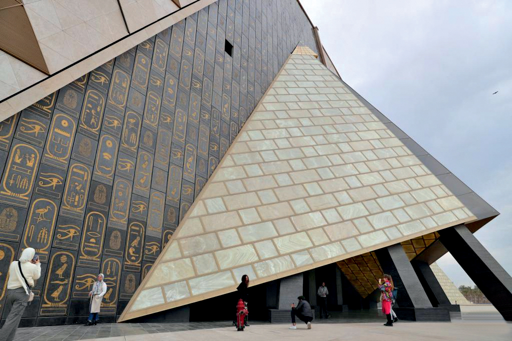 Tourists pose for photos at the entrance of the Grand Egyptian Museum in Giza, Egypt, Feb. 11, 2023. Constructed on approximately 500,000 square meters, the Grand Egyptian Museum is located nearby the Giza Pyramids. Still under construction, some parts of the museum's area are put into trial operation. It will be, after opening, one of the largest museums in the world presenting a heritage of ancient civilization. (Xinhua/Sui Xiankai)