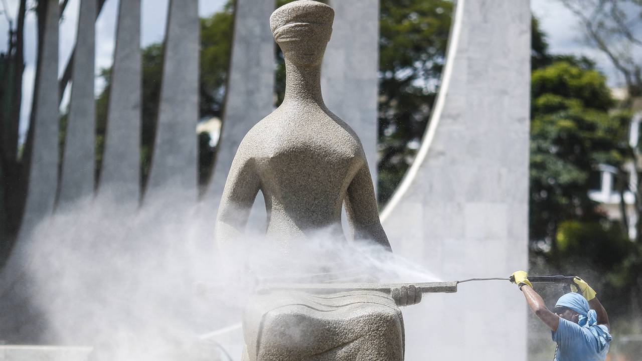 FAXINA - Funcionário lava estátua pichada no Supremo: primeira leva de acusados pode pegar 25 anos de prisão