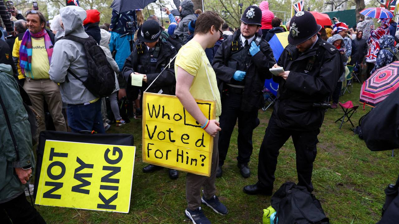 An anti-monarchy protester stands with police officers as people gather at The Mall during the coronations of Britain's King Charles III and Britain's Camilla, Queen Consort at Westminster Abbey in central London on May 6, 2023. - The set-piece coronation is the first in Britain in 70 years, and only the second in history to be televised. Charles will be the 40th reigning monarch to be crowned at the central London church since King William I in 1066. Outside the UK, he is also king of 14 other Commonwealth countries, including Australia, Canada and New Zealand. Camilla, his second wife, will be crowned queen alongside him, and be known as Queen Camilla after the ceremony. (Photo by PAUL CHILDS / POOL / AFP)
