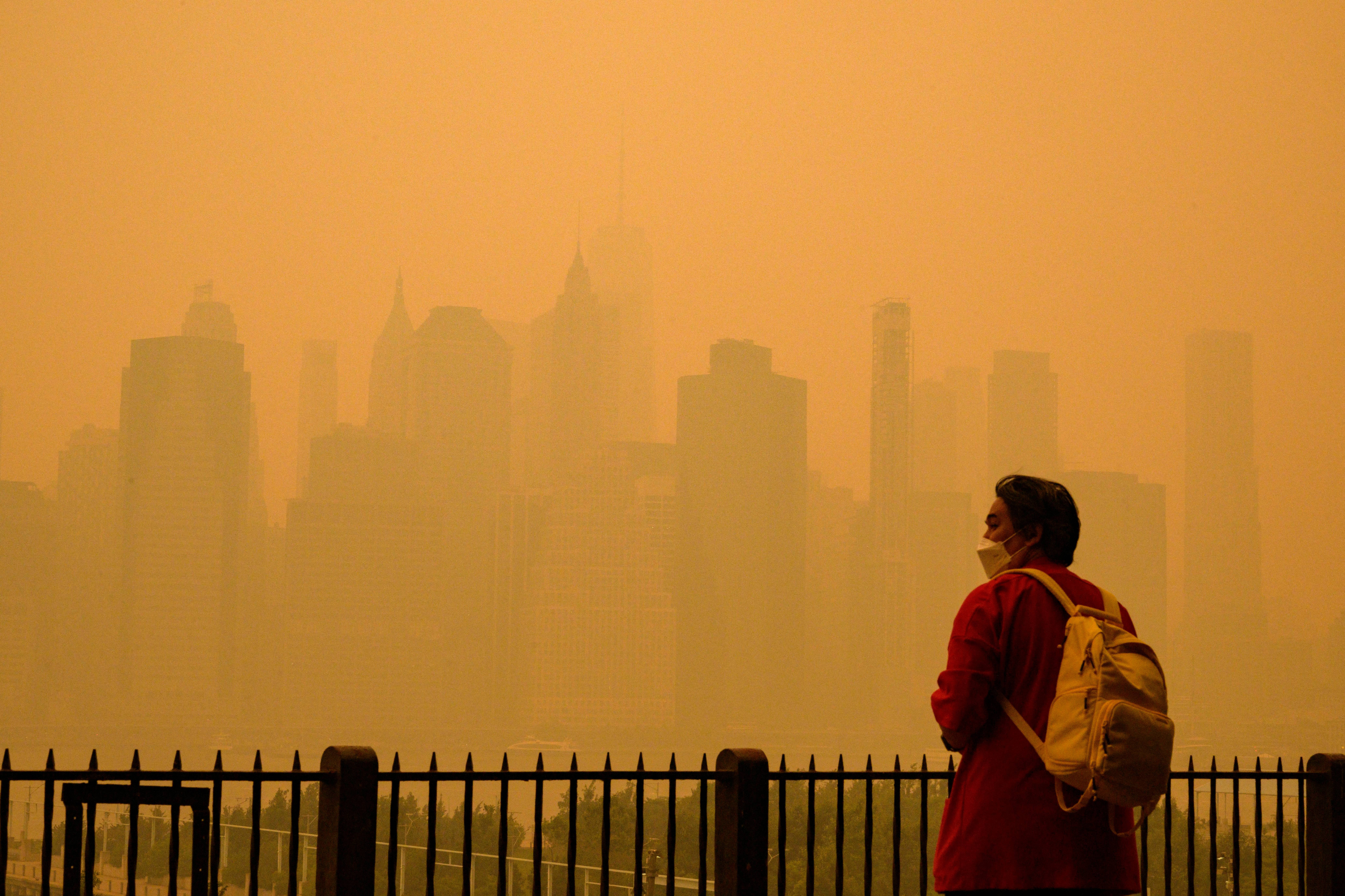 A person wears a face mask as smoke from wildfires in Canada cause hazy conditions in New York City on June 7, 2023. An orange-tinged smog caused by Canada's wildfires shrouded New York on Wednesday, obscuring its famous skyscrapers and causing residents to don face masks, as cities along the US East Coast issued air quality alerts. (Photo by ANGELA WEISS / AFP)