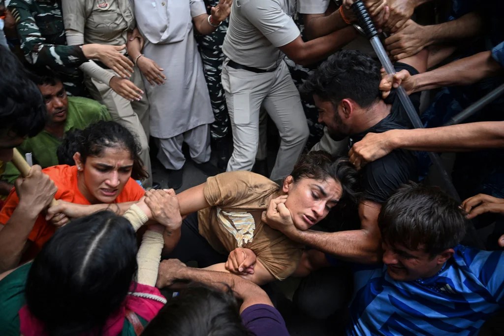 As lutadoras Sangeeta Phogat, à esquerda, e Vinesh Phogat, ao centro, são detidas pela polícia enquanto tentavam marchar para o novo parlamento da Índia durante um protesto contra Brij Bhushan Singh em Nova Delhi -