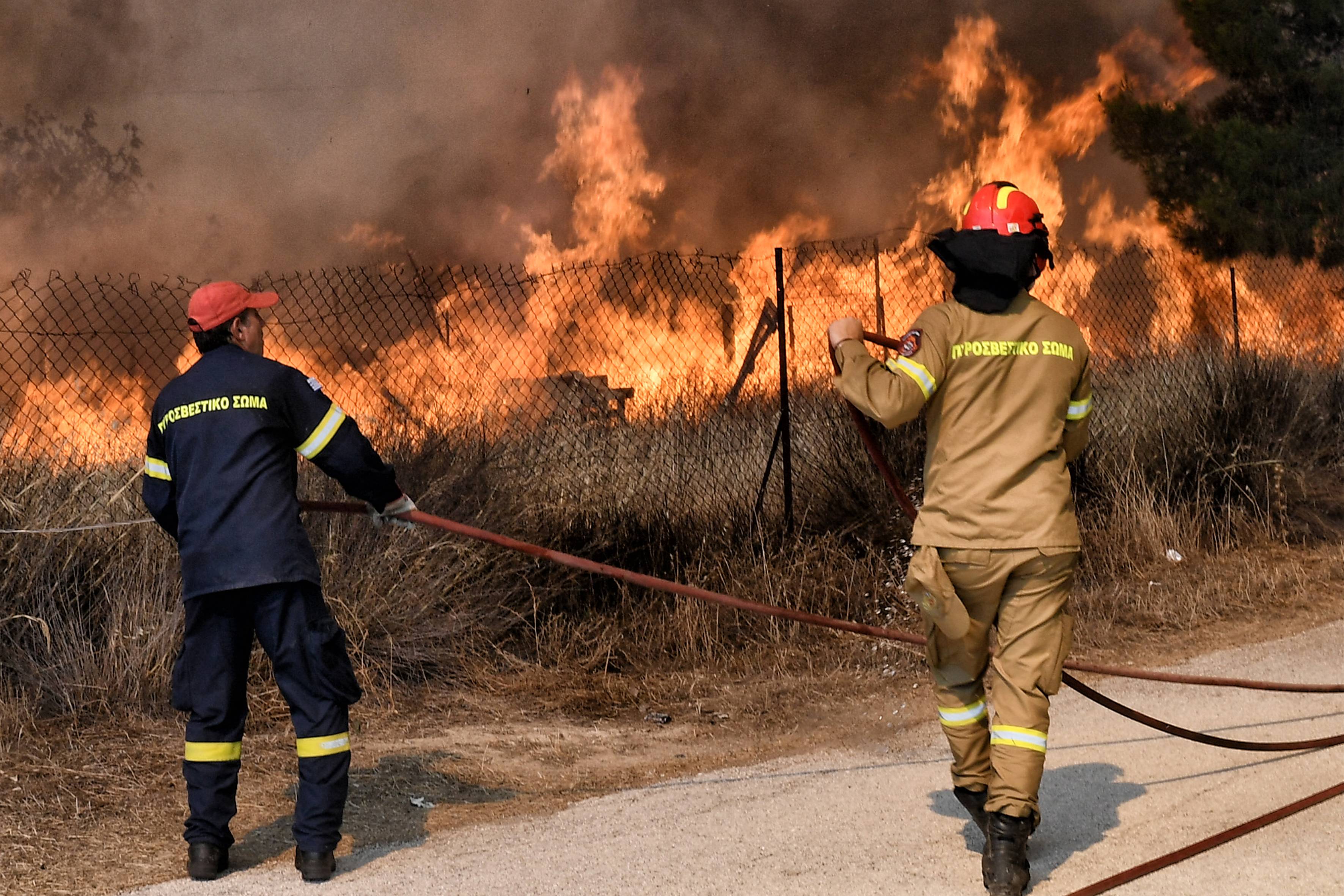 Firemen battle the wildfire in the settlement of Irini, near the resort town of Loutraki, some 80 kilometres east of Athens, on July 17, 2023. Greek police on July 17, 2023 arrested a man suspected of starting an ongoing wildfire near Athens fuelled by a heatwave and strong winds, firefighters said."Police carried out the arrest of a foreigner who allegedly caused the fire" in Kouvaras, around 50 kilometres (30 miles) southeast of Athens, said fire service spokesman Yannis Artopios. (Photo by Valerie GACHE / AFP)