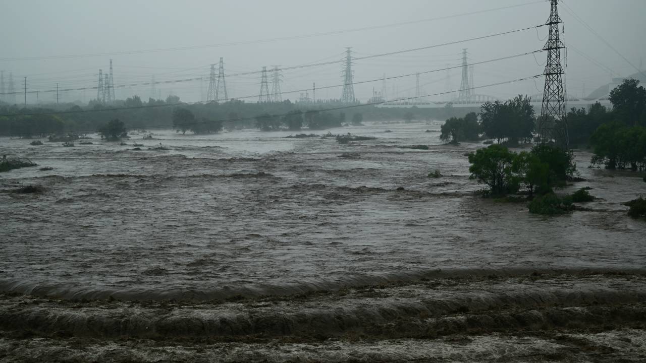View of the Yongding River overflow next to the Winter Olympic Ski Jump in Shijingshan, Beijing on August 1, 2023. At least 11 people were killed and 13 were missing after heavy rains lashed Beijing, state media said on August 1, in downpours that have submerged roads and deluged neighbourhoods with mud. (Photo by Pedro PARDO / AFP)
