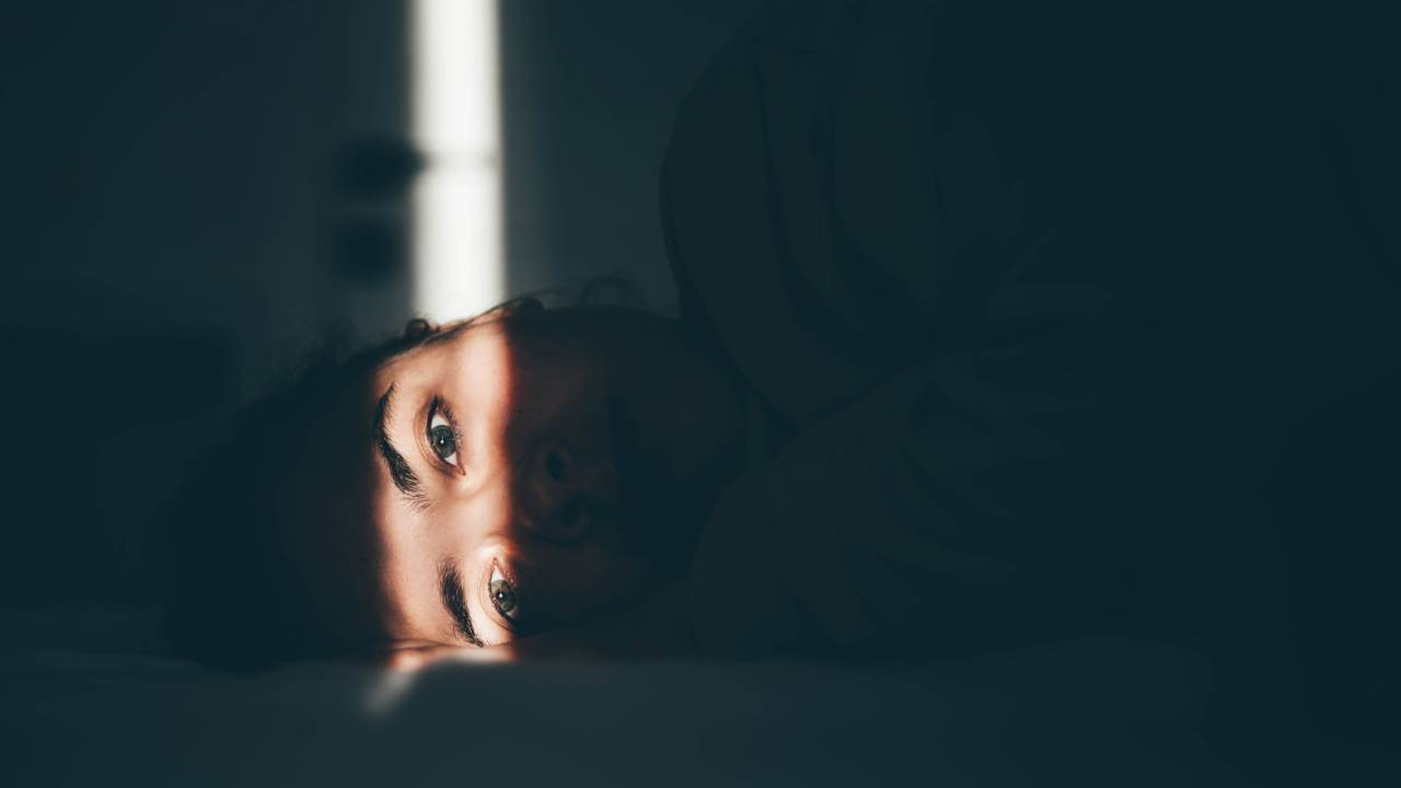 Worried young woman lying on bed at home.