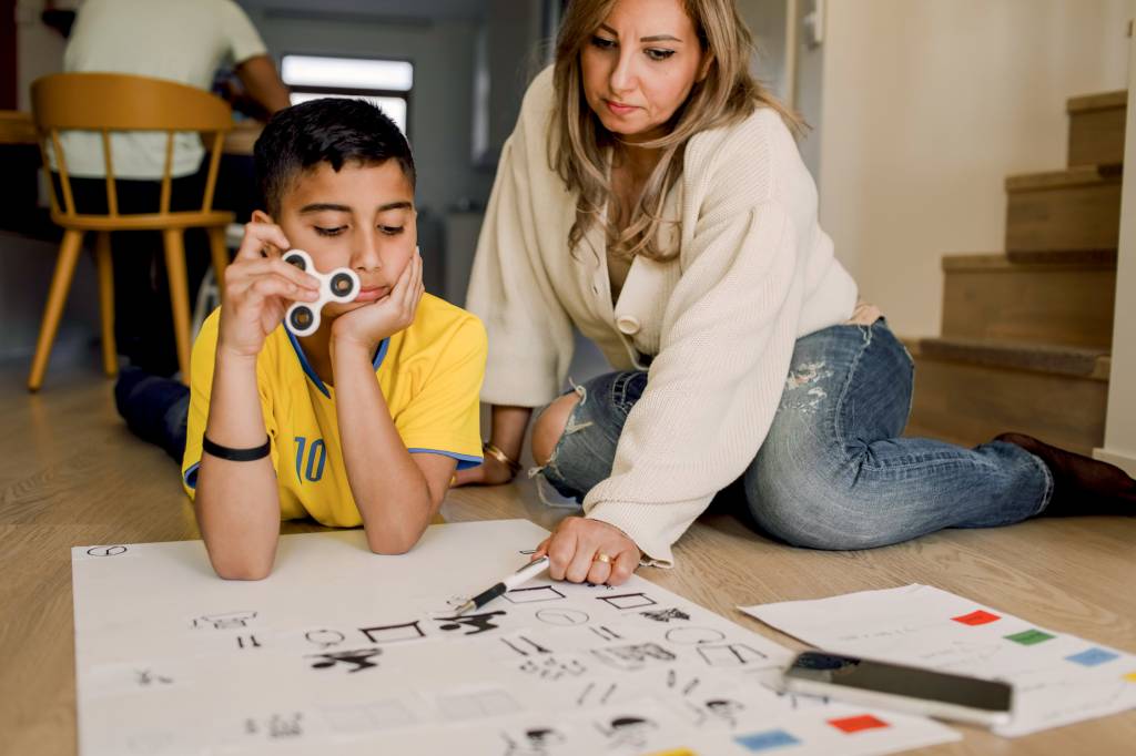 Mother teaching son while sitting at home ALÉM DOS REMÉDIOS - Em casa e na escola: tratamento envolve métodos de psicoeducação e treinamento dos pais