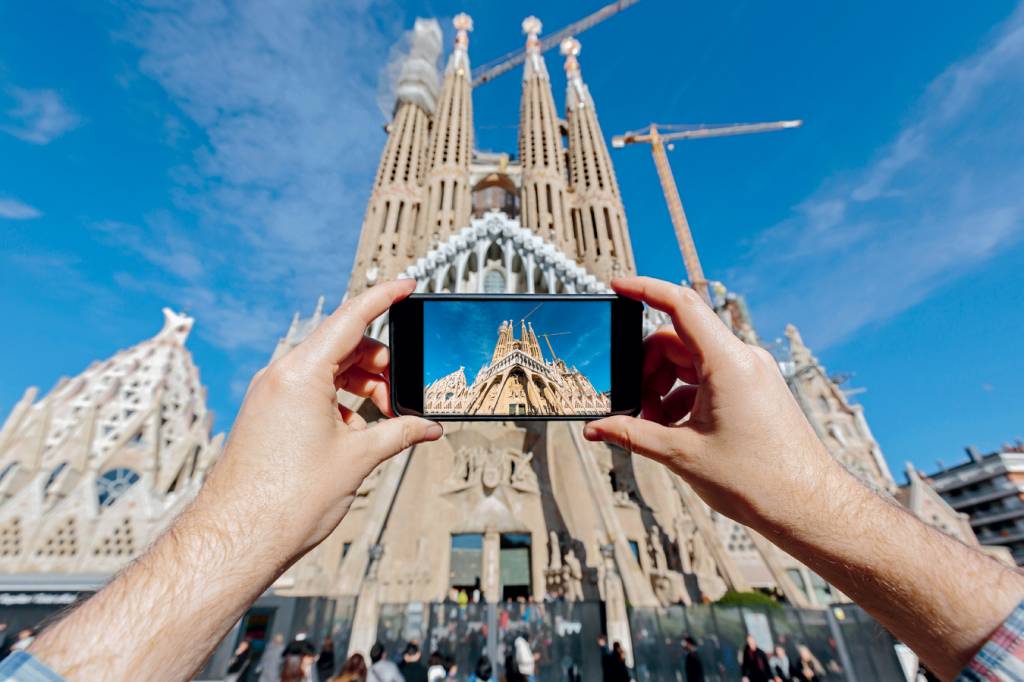 Tourist photographing Sagrada Familia in Barcelona with smartphone EM ALTA - Sagrada Família, marco de Barcelona: interesse cada vez maior
