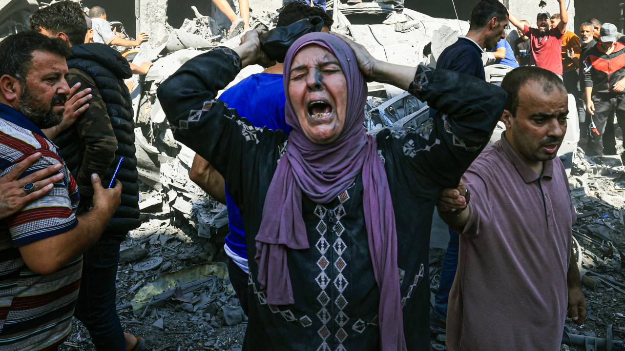 EDITORS NOTE: Graphic content / A Palestinian woman reacts as others rush to look for victims in the rubble of a building following an Israeli strike in Khan Yunis in the southern Gaza Strip on October 17, 2023, amid the ongoing battles between Israel and the Palestinian group Hamas. Thousands of people, both Israeli and Palestinians have died since October 7, 2023, after Palestinian Hamas militants based in the Gaza Strip, entered southern Israel in a surprise attack leading Israel to declare war on Hamas in Gaza on October 8. (Photo by Mahmud HAMS / AFP)