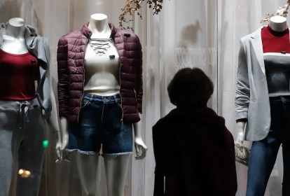 Mulher observa roupas em vitrina de loja