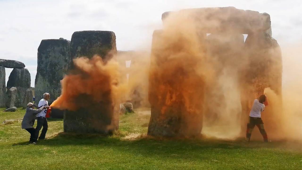 Ativistas da Just Stop Oil pulverizando tinta em pó laranja em Stonehenge, Inglaterra.