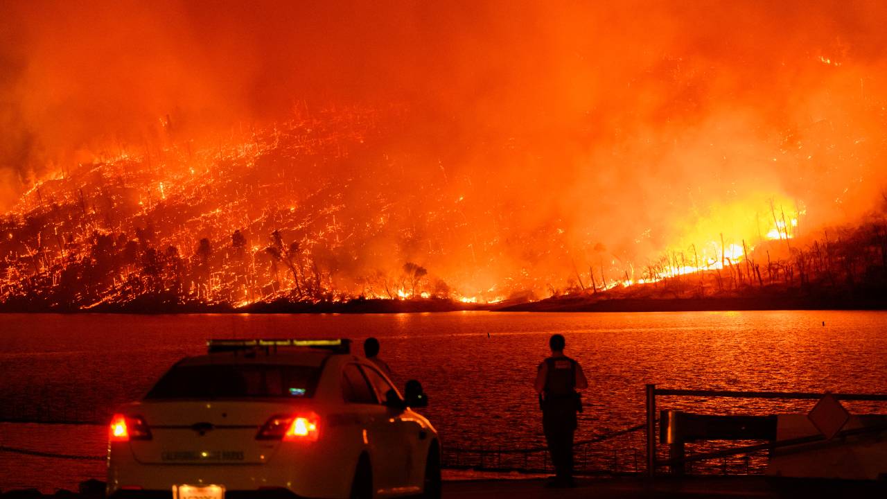 Law enforcement members watch as the Thompson fire burns over Lake Oroville in Oroville, California on July 2, 2024. A heatwave is sending temperatures soaring resulting in red flag fire warnings throughout the state. (Photo by JOSH EDELSON / AFP)