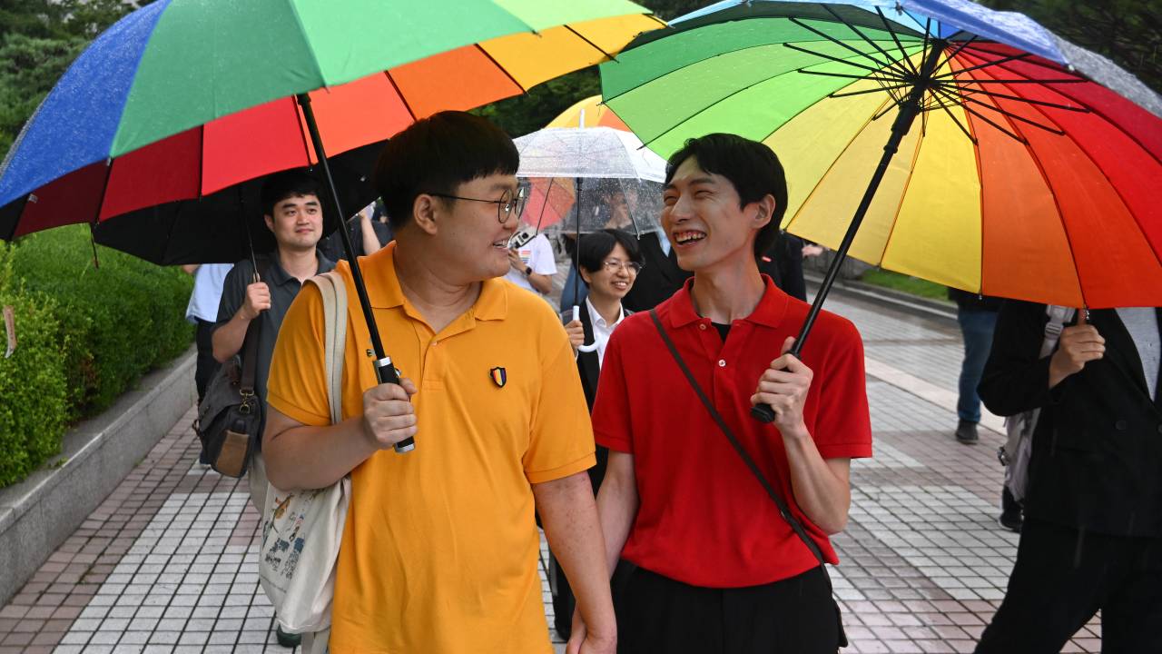 South Korean same-sex couple So Seong-wook (L) and Kim Yong-min (R) leave the Supreme Court building in Seoul on July 18, 2024 after the court's ruling on a lawsuit against the National Health Insurance Service for their dependent family status. South Korea's Supreme Court recognised new rights for same-sex couples on July 18, saying the state must provide health insurance for a gay man's partner in a landmark ruling that left activists weeping for joy. (Photo by Jung Yeon-je / AFP)