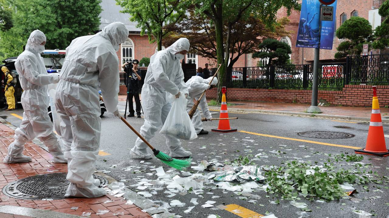 South Korean officials clean up the contents of a trash-carrying balloon sent by North Korea after it landed on a street in Seoul on July 24, 2024. This is the tenth time the North has sent the balloons across the border this year in what it claims is retaliation for anti-regime propaganda balloons launched by South Korean activists. (Photo by YONHAP / AFP) / - South Korea OUT / NO ARCHIVES - RESTRICTED TO SUBSCRIPTION USE